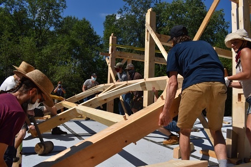 A team of people working together to raise part of a timber frame structure.