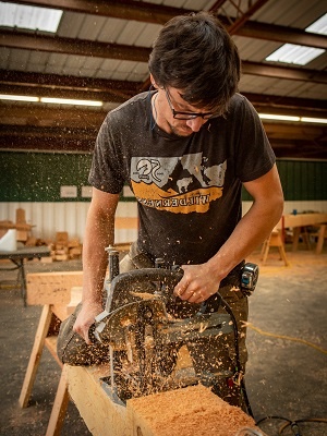 A timber framer using a power tool on a timber.